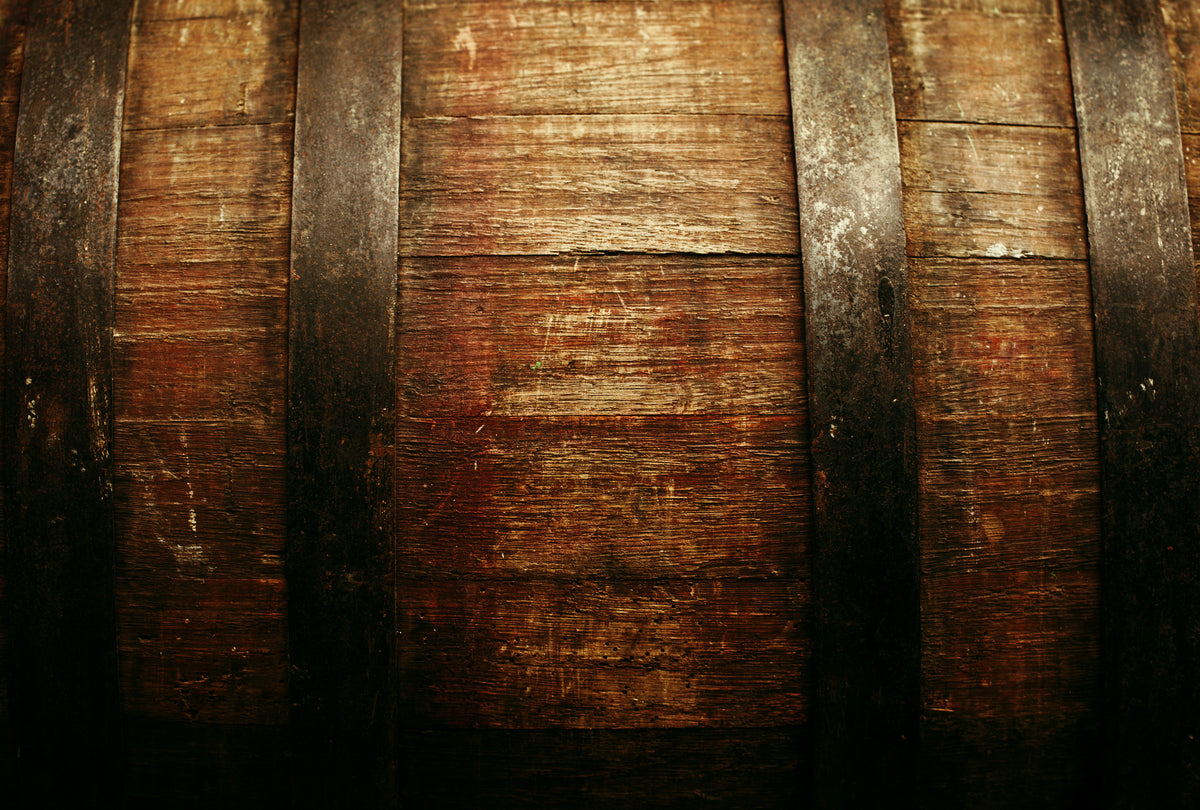Close-up of a rustic wooden barrel surface with dark metal hoops and visible wood grain texture.