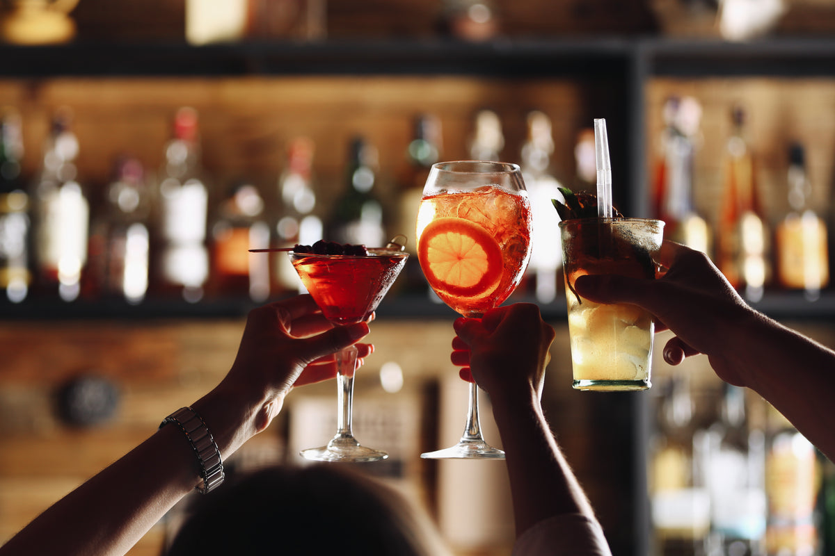 Three people holding cocktails in a bar setting